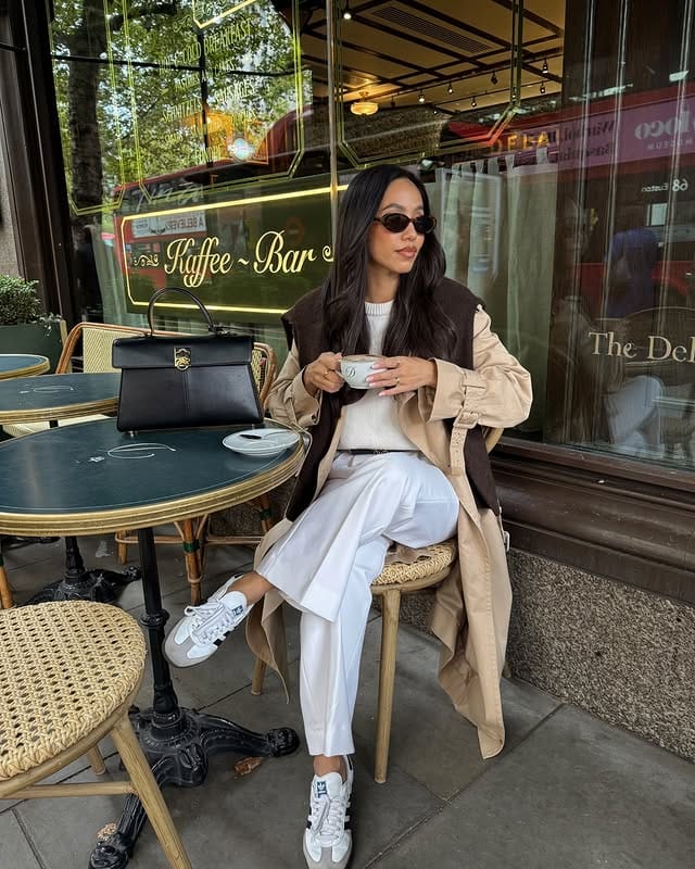 Stylish woman with sunglasses, dressed in casual clothes and straight hairstyle, enjoying coffee at outdoor cafe - bar on a sunny morning.