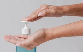 Mão apertando pump de sabonetes faciais não comedogênicos.