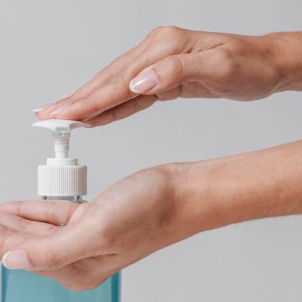 Mão apertando pump de sabonetes faciais não comedogênicos.