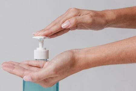 Mão apertando pump de sabonetes faciais não comedogênicos.